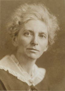 Headshot of a woman looking at the camera in sepia tones.