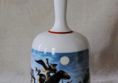 a white ceramic bell decorated with an image of Paul Revere on horseback